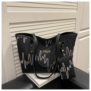 Detail of black embroidered tote bag set with textured fabric and small coin purse