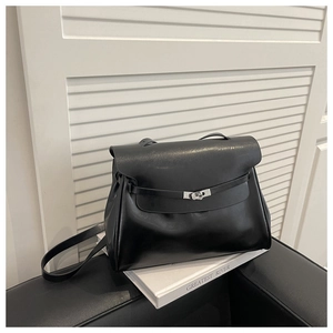 Detail of vintage black leather tote featuring a silver twist lock and reinforced handle