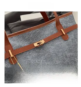 Close-up of grey felt tote bag with brown leather trim and golden metal turn lock