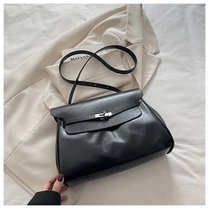 Detail of black leather crossbody bag with metallic buckle on a beige blazer