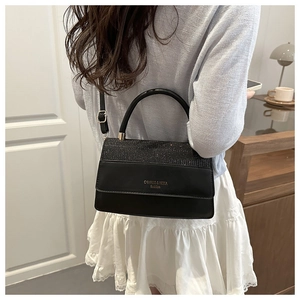 Detail of black mini square bag featuring glitter patchwork and golden fashion text
