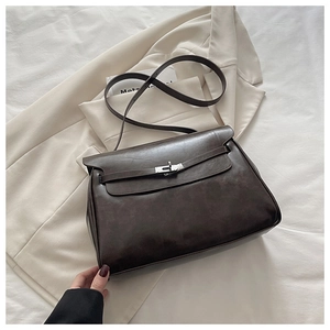 Detail of dark brown vintage flap bag with silver metal twist lock on beige fabric