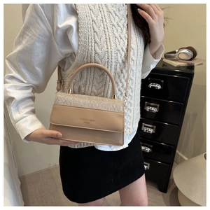 Detail of beige crossbody bag with rhinestone flap shown with model outfit