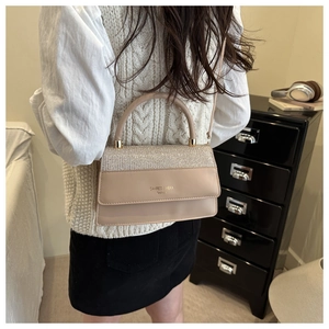 Detail view of beige crossbody bag with glitter panel and elegant circular handle