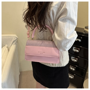 Detail of pink crossbody bag with purple glitter flap and polished metal handle accents