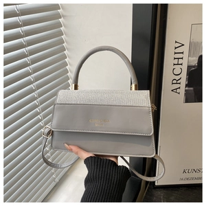Detail of grey leather tote with silver glitter flap and gold logo on front