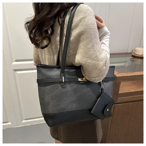 Detail view of grey matte tote bag with black leather base and gold buckle hardware accents