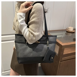 Detail view of a large two-tone tote bag featuring grey canvas and a gold metal twist lock