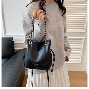 Detail of black leather bucket bag with silver chain strap and drawstring closure