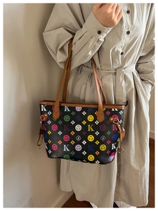 Fashionable tote bag with colorful monogram print styled with a beige trench coat