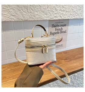 Detail view of white crocodile pattern box bag with premium gold dual-zipper closure