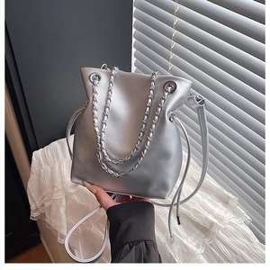 Detail of silver metallic bucket bag with leather chain strap and wrinkled texture design