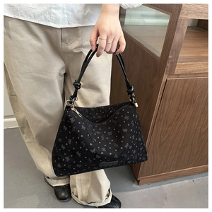 Close-up of black corduroy tote bag with butterfly prints and knotted handle detail