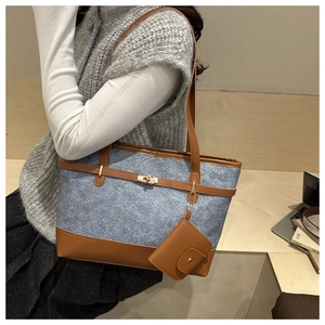Detail of color-block denim tote bag featuring brown leather straps and gold buckle lock