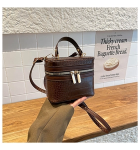 Detail of brown crocodile pattern box bag with dual zipper and top handle texture