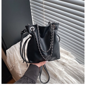 Close-up of black leather bucket bag with silver metal eyelets and chain straps