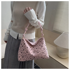 Detailed close-up of pink corduroy tote bag featuring black bow and heart print patterns