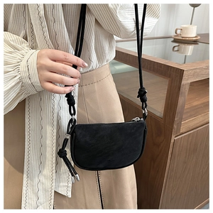 Close-up of a black minimalist crossbody phone bag with adjustable shoulder strap and silver hardware