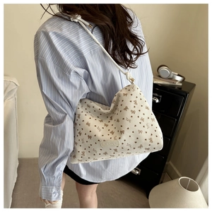 Detail of the white tote bag with heart patterns and knotted rope shoulder strap