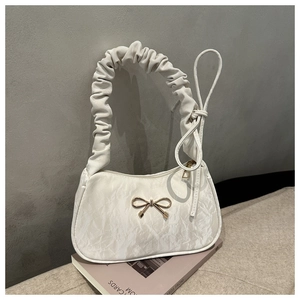 Détail de sac sous le bras blanc avec nœud doré et poignée plissée élégante