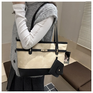 Detail of canvas tote bag with black leather straps and gold buckle worn by model