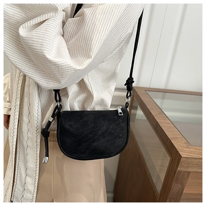 Close-up of minimalist black matte crossbody saddle bag with knotted strap details