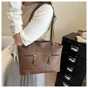 Détail d'un sac cabas en cuir marron avec coutures contrastées et zips dorés élégants