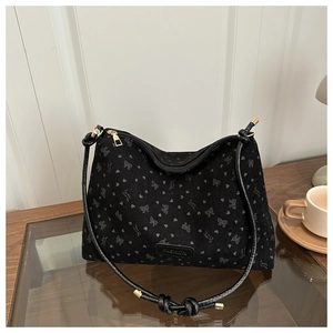 Detail of black tote bag with heart bow print and adjustable gold hardware strap