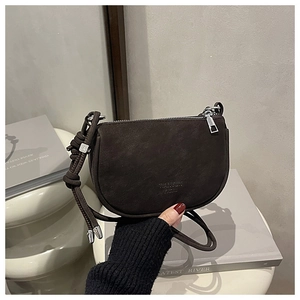 Detail view of coffee brown saddle bag with matte finish and knotted shoulder strap