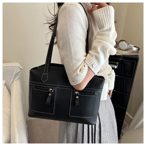 Détail du sac cabas noir avec coutures blanches contrastées et poches avant zippées pratiques