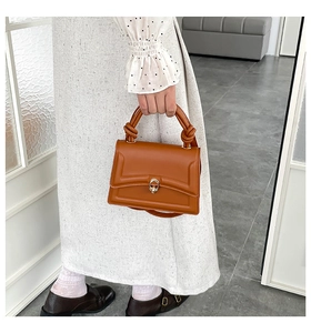Close-up of caramel brown leather handbag featuring a twist handle and metal twist lock