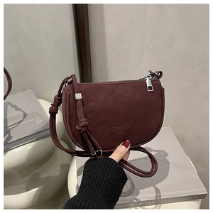Detail of burgundy matte crescent bag featuring silver hardware and knotted shoulder strap