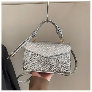 Detail of silver textured envelope bag with knotted handle and metallic finish