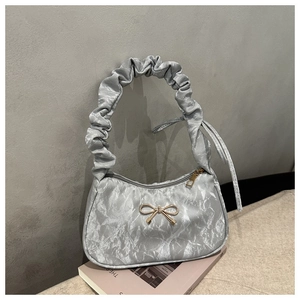 Détail du sac à bandoulière plissé argenté avec nœud doré et poignée à volants
