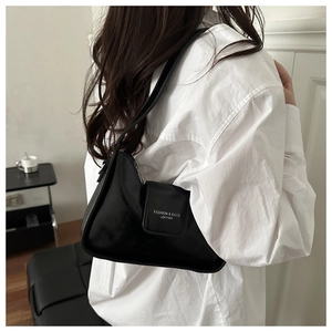 Close-up of black glossy leather underarm bag featuring the stylish brand logo on flap