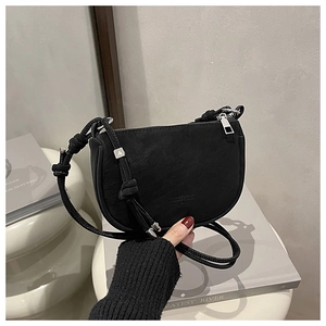 Detail of black matte leather saddle bag featuring silver 'A' hardware and adjustable strap