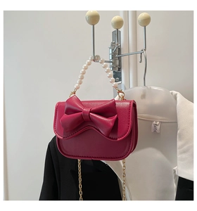 Detail of rose red mini bag with pearl handle, chain strap, and large bow decoration