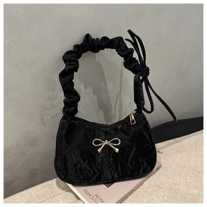 Détail du sac à bandoulière froncé noir avec boucle nœud doré et bandoulière plissée
