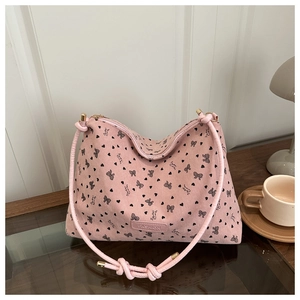 Detail of warm pink corduroy tote bag with heart print on a wooden coffee table