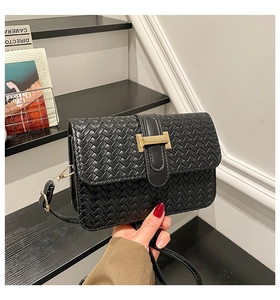 Close-up of black woven leather handbag featuring a signature gold H-shaped metal buckle