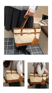 Detail of canvas tote bag with brown leather trim and golden metal twist lock closure
