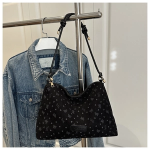 Detail of black bow-print tote bag with fashion label and textured rope shoulder straps