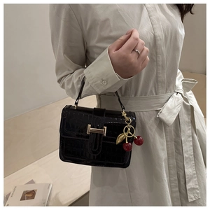 Detail view of black stone pattern small square bag with cherry charm and gold buckle