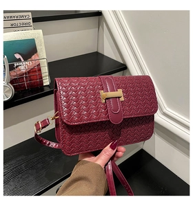 Detail of burgundy leather woven shoulder bag with a gold metal decorative buckle
