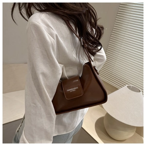Detail of adjustable strap and leather texture on a brown baguette shoulder bag