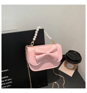 Detailed view of a pink bow mini crossbody bag with pearl handle and golden chain