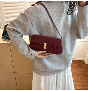 Dettaglio borsa baguette bordeaux con stampa leopardata e fibbia dorata su modella