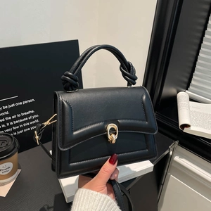 Black PU leather handbag with gold lock and knot handle in elegant urban setting
