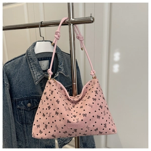 Detail of pink corduroy tote bag with black bow patterns and knotted shoulder strap