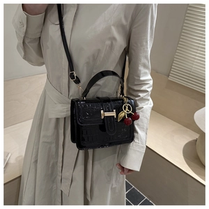 Detail of black faux-crocodile leather handbag with gold H buckle and cherry charm accessories